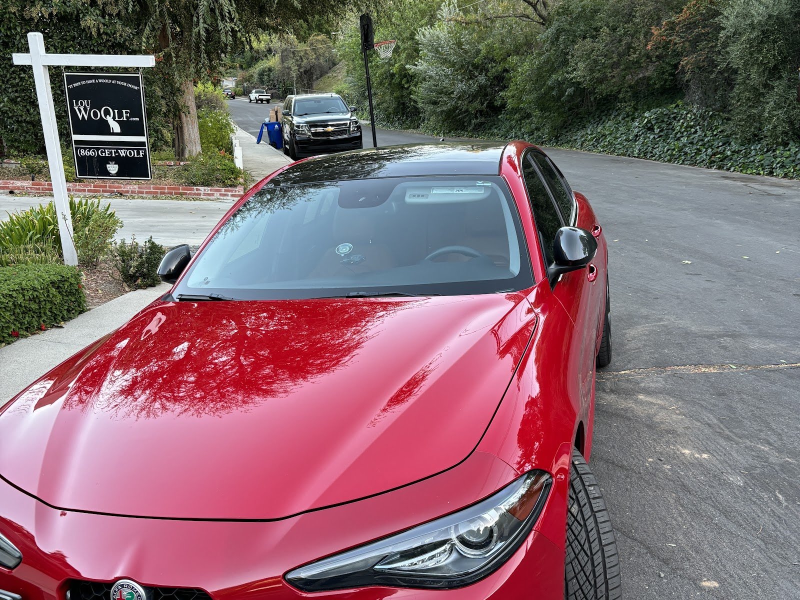 Red Alfa Romeo sedan repaired at Sako's, parked outside the shop